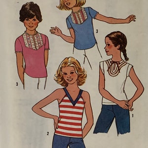 Puede incluir: Un patrón de costura para tres blusas diferentes para niñas. Las blusas son una blusa rosa con cuello blanco, una blusa azul con cuello blanco y un top sin mangas de rayas rojas y blancas. El patrón es para la talla 10.