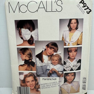 May include: A vintage McCall's sewing pattern envelope featuring the number P973 and the text "One Envelope Une Pochette". The pattern showcases a white lace collar with a central bow. The envelope includes a photograph of five women modelling the collar in various styles.