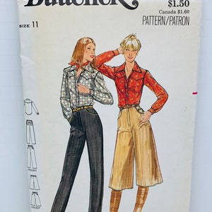 Peut inclure: Patron de couture Butterick vintage 5625, taille 11, avec des illustrations de deux femmes en tenues des années 1970. L'une porte une chemise à carreaux et un pantalon foncé, l'autre une chemise fleurie et un pantacourt beige. Le patron inclut des instructions.