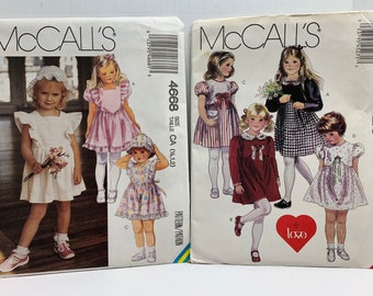 May include: Two sewing pattern envelopes for children's dresses. The left envelope shows a white dress with a ruffled collar and a pink dress with a ruffled hem. The right envelope shows a red dress with a white collar and a white and black checkered dress. The text on the envelopes reads "McCall's" and includes the pattern numbers 4668 and 4527.