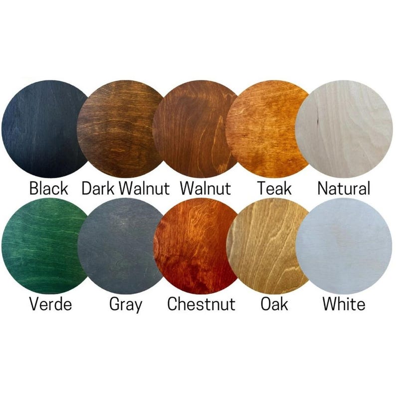 May include: A collection of ten circular wooden samples arranged in two rows. The top row shows Black, Dark Walnut, Walnut, Teak, and Natural finishes. The bottom row displays Verde, Gray, Chestnut, Oak, and White finishes, each labeled below.