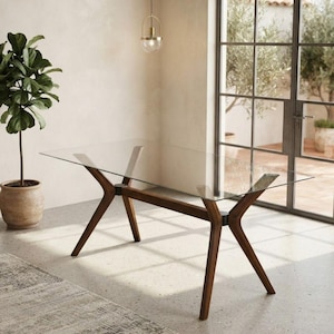 May include: A rectangular dining table featuring a clear glass top supported by a dark brown wooden base with four angled legs that meet at central joints, creating a distinct X-shaped structure at each end of the table frame.