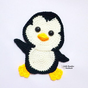 May include: A crocheted penguin with black and white yarn, yellow feet, and black eyes. The penguin is standing on a white background.