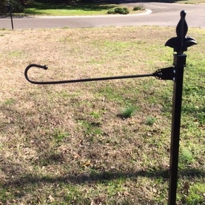 May include: Black metal garden flag stand with a decorative finial and a hook for hanging a flag.
