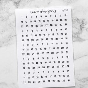 May include: A small white sticker sheet with black numbers arranged in a calendar format. The sheet includes the text "jemdesigns" and "Q050". The numbers are arranged in rows of 1-10, 11-21, and 22-31.