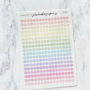 May include: A sheet of 5mm pastel rainbow dot stickers. The sheet has 10 rows of 10 dots each, with each row a different pastel colour. The colours are pink, light pink, purple, light blue, green, yellow, and light yellow. The sheet is labelled "5mm dots by jemdesigns C163".