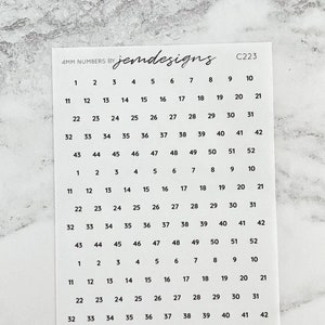 May include: A white sticker sheet featuring black numbers from 1 to 52, arranged in rows and columns. The text "4MM NUMBERS by jemdesigns" is printed at the top, along with the code "C223". The numbers are in a simple, clean font.