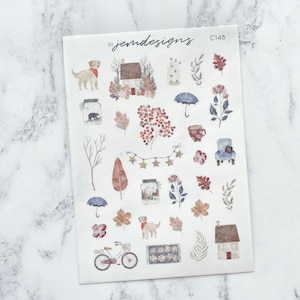 May include: A sheet of stickers featuring a variety of autumn-themed illustrations, including houses, dogs, leaves, a cup of coffee, an umbrella, and a bicycle. The stickers are printed on a white background and have a watercolour-like style. The text "by jemdesigns C148" is printed in the top right corner of the sheet.
