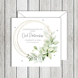 May include: A white card with the words "CONGRATULATION ON YOUR CIVIL PARTNERSHIP" in script. It has a gold circular design with floral and greenery. The names "CHARLOTE & TOM" and the date "21ST SEPTEMBER 2025" are also included. The card is in an envelope.