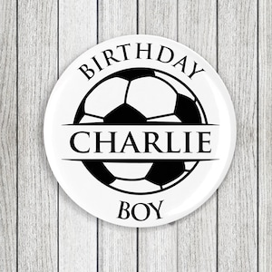 May include: White round plate with a black and white football design. The text "Birthday" is above the ball, "Charlie" is in a banner across the middle, and "Boy" is below the ball.