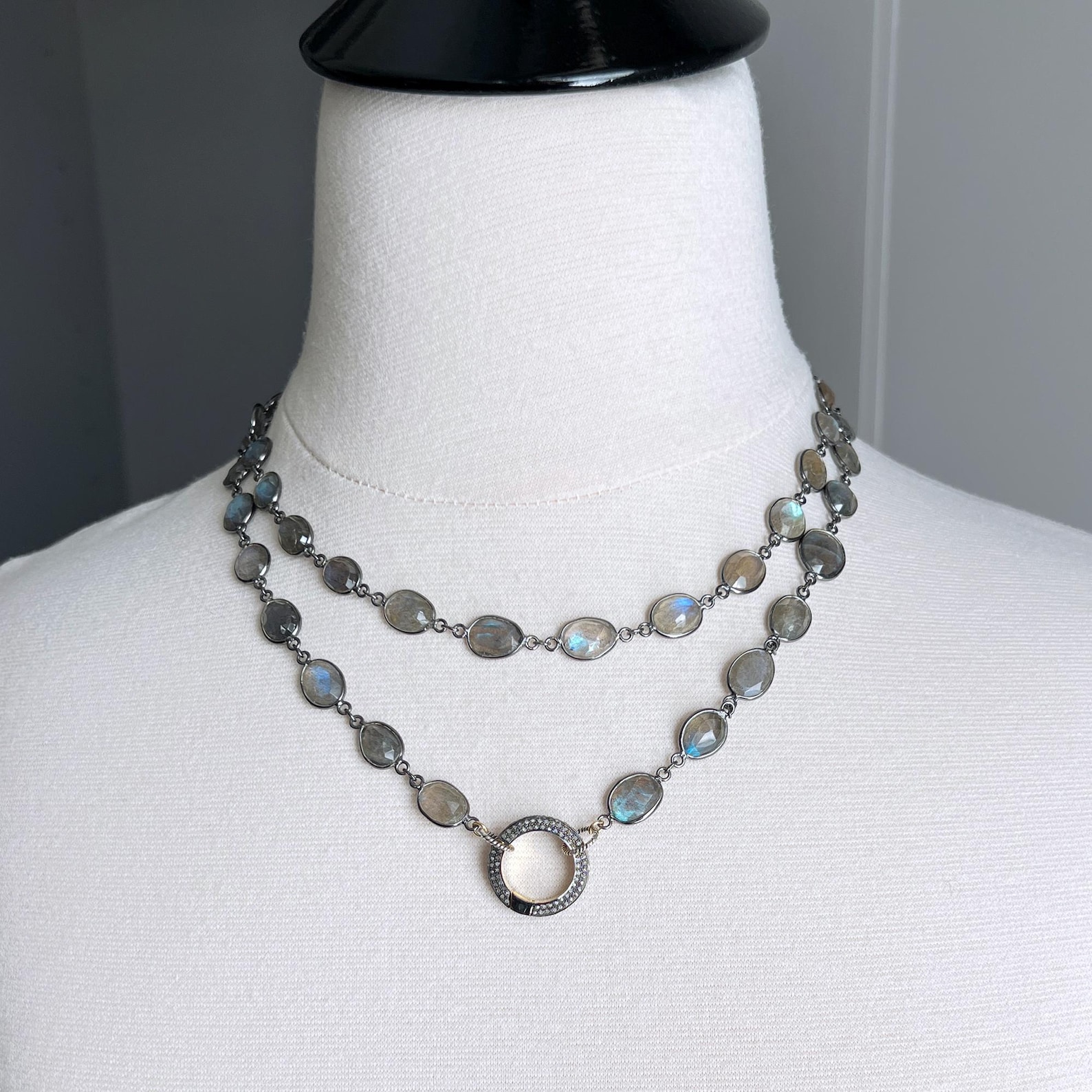 Double strand labradorite necklace with circular silver pendant on white mannequin.