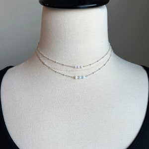 May include: A silver layered choker necklace with a row of five white opal beads.