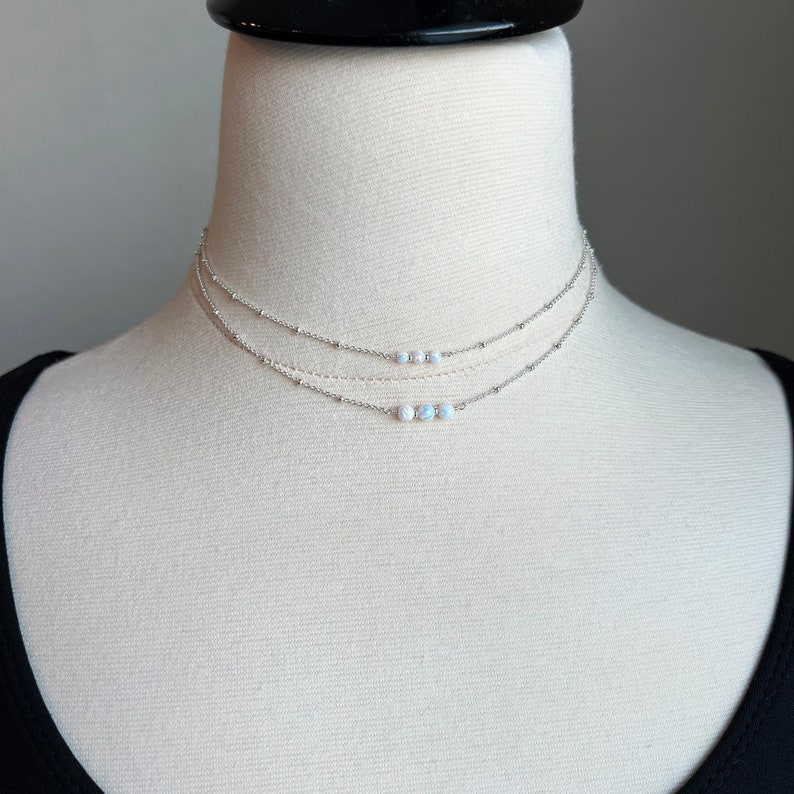May include: A silver layered choker necklace with a row of five white opal beads.