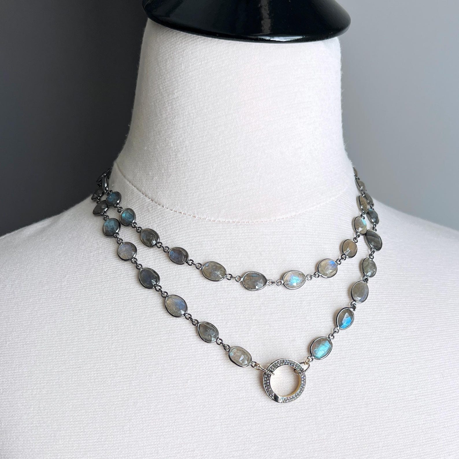 Double strand labradorite necklace with circular silver pendant on white mannequin.