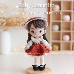 May include: A handmade crochet doll, featuring a red and white dress, a matching hat, and black shoes. The doll has brown hair and is standing on a wooden base. Text on the image reads "Baby Amanita" and "Princess Size PDF Crochet Patterns."