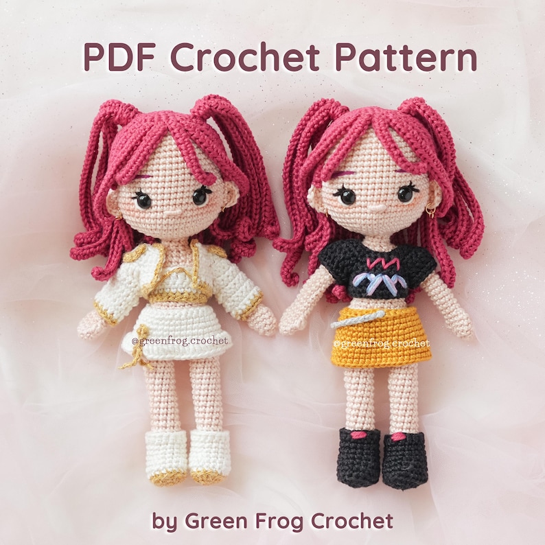 May include: Two handmade crochet dolls with pink hair in pigtails. One doll wears a white and gold outfit, the other a black top and yellow skirt. The text "PDF Crochet Pattern" and "by Green Frog Crochet" are visible.