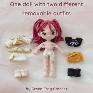 May include: A crocheted doll with pink hair and two sets of removable outfits. One outfit is white with gold trim, and the other includes a black top, a yellow purse, and black boots. The text reads "One doll with two different removable outfits."