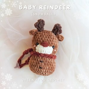 May include: A brown crocheted reindeer toy with a white face and red nose. The toy is wearing a red scarf and has the text "BABY REINDEER (SNOWBALL)" above it and "GREEN FROG CROCHET" below it.