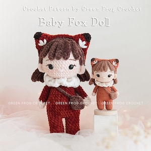 May include: Two crocheted fox dolls, one larger than the other, both wearing red and brown outfits with white accents. The dolls have brown hair and black eyes. The larger doll is holding a small brown bag. The dolls are sitting on a white surface with a pink background. Crochet Pattern by Green Frog Crochet Baby Fox Doll