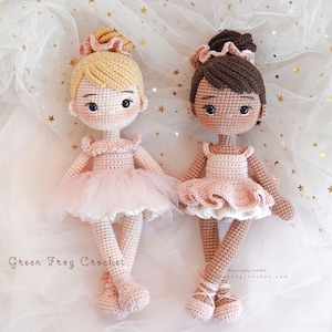 Puede incluir: Dos mu&ntilde;ecas de bailarina de crochet, una con cabello rubio y otra con cabello casta&ntilde;o, con tut&uacute;s rosas y zapatos de ballet blancos. Las mu&ntilde;ecas est&aacute;n colocadas sobre un fondo blanco con estrellas doradas brillantes.
