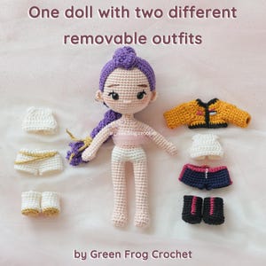 May include: A crocheted doll with purple hair and two sets of removable outfits. One outfit includes a white top and shorts with gold trim. The other outfit includes a yellow jacket, white top, and navy shorts with pink trim. Text: One doll with two different removable outfits.