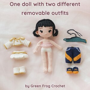 May include: A crocheted doll with black hair and two sets of removable outfits. One outfit is white with gold trim, and the other is navy blue with yellow accents. The doll is standing next to the outfits. Text on the image reads "One doll with two different removable outfits" and "by Green Frog Crochet."