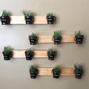Peut inclure: Un jardin d'herbes suspendu au mur avec de petits pots en métal et des étiquettes en ardoise. Les étiquettes indiquent "Persil", "Thym", "Ail", "Manger", "Nettoyer", "Vivre", "Vous", "Obtenu", "Ceci", "Votre", "Propre", et "Texte".