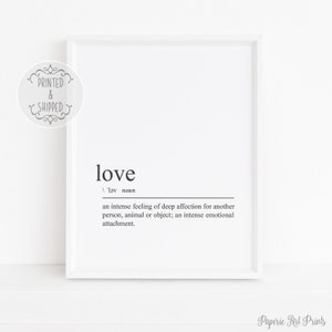 Peut inclure: Une impression encadrée blanche avec le mot "love" en noir, ainsi que sa définition. La définition décrit un sentiment intense d'affection. L'impression est dans un cadre blanc et est affichée sur une surface blanche.