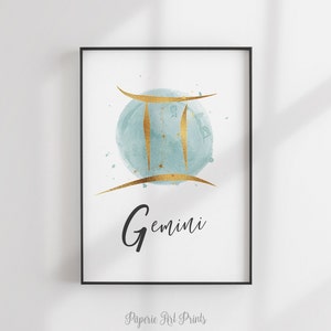 May include: A watercolor print featuring the Gemini zodiac sign in gold with a blue watercolor background. The word "Gemini" is written in black below the sign.