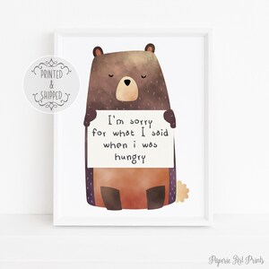May include: A watercolor illustration of a brown bear holding a sign that says "I'm sorry for what I said when I was hungry".
