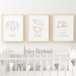May include: Three framed prints with watercolor illustrations of baby elephants. The first print features a family of elephants with the word "LOVE" below. The second print features a single elephant with a blue balloon and the words "HELLO WORLD". The third print features two elephants sleeping on a cloud with the words "DREAM BIG LITTLE ONE".