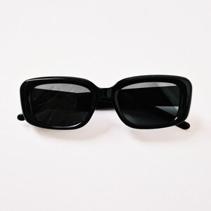 K&ouml;nnte beinhalten: Schwarze quadratische Sonnenbrille mit schwarzen Rahmen und Gl&auml;sern.