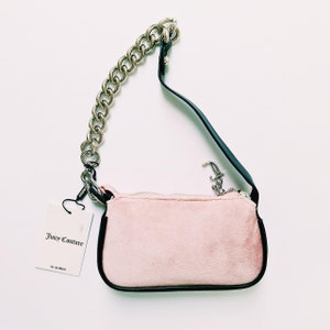 May include: A pink velvet handbag with a silver chain strap and a black leather strap. The bag has a Juicy Couture tag attached to it.