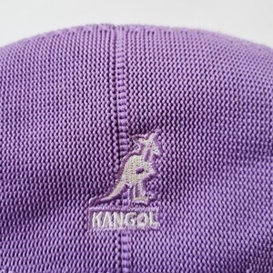 May include: Purple knitted Kangol brand baseball cap with a white embroidered kangaroo logo.