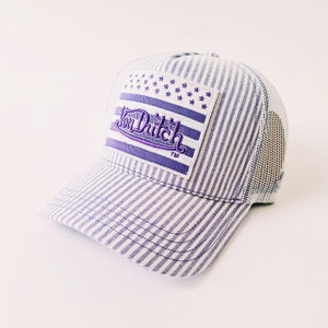 May include: A striped baseball cap with a white mesh back and a curved brim. The front panel features a patch with the text "Von Dutch" in purple script, along with a design of stars and stripes.