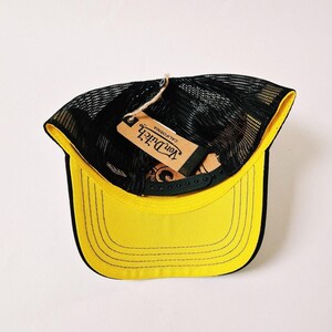 Peut inclure: Casquette de camionneur jaune et noir avec un dos en filet et une visi&egrave;re incurv&eacute;e. L'&eacute;tiquette indique "Von Dutch California". Un style classique, adapt&eacute; aux tenues d&eacute;contract&eacute;es.