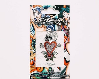May include: A peel and stick crystal decal featuring a skull and crossbones with a red heart in the center. The decal is surrounded by a floral design and is made by Ed Hardy.
