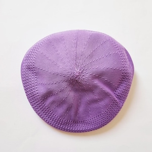 May include: A purple knitted beret with a textured pattern.