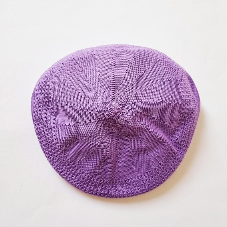 May include: A purple knitted beret with a textured pattern.
