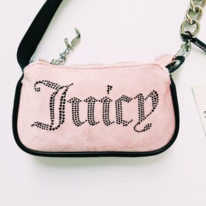 May include: A pink velvet handbag with a black strap and a silver chain. The bag has the word "Juicy" spelled out in black rhinestones.