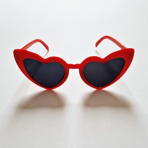 May include: Red heart-shaped sunglasses with black lenses.