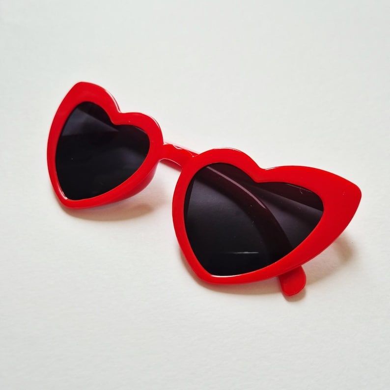 May include: Red heart-shaped sunglasses with black lenses.