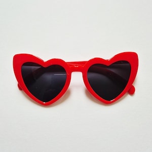 May include: Red heart-shaped sunglasses with black lenses.