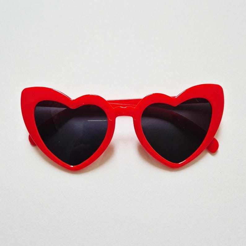 May include: Red heart-shaped sunglasses with black lenses.