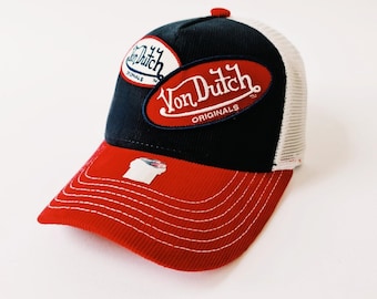 May include: A red, white, and blue trucker hat with a navy blue crown and a red bill. The hat has a white mesh back and features a large "Von Dutch Originals" logo in red and white on the front.