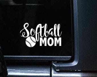 May include: A white vinyl decal applied to a vehicle window featuring the text Softball MOM in a combination of script and block lettering, with a graphic of a softball replacing the letter O in the word Softball.