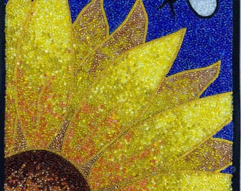 May include: A beaded sunflower with a brown center and yellow petals against a blue background. A white and yellow beaded bee is flying above the sunflower.