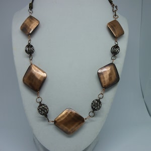 May include: A copper necklace with square-shaped pendants and wire ball accents.