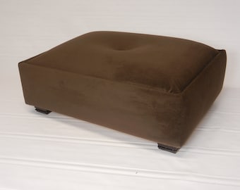 May include: A brown rectangular ottoman with a tufted top and black legs.
