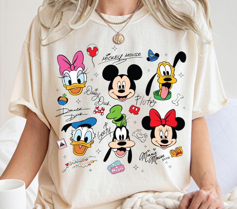 A person wearing a white t-shirt with various Disney characters and text printed on it.